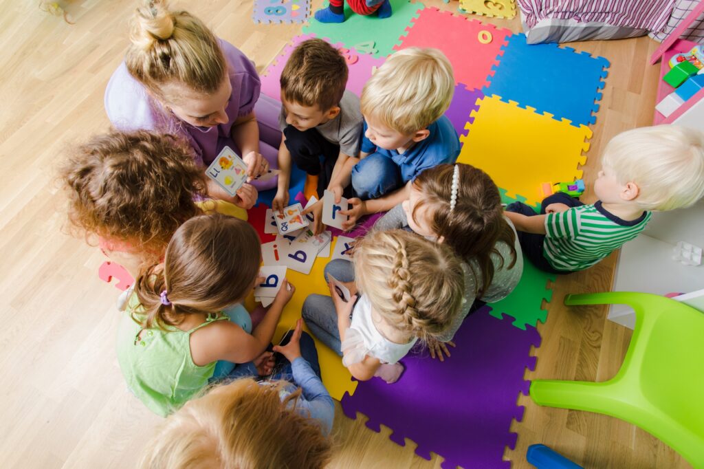 Kinder in einer Kita spielen mit einer Erzieherin.